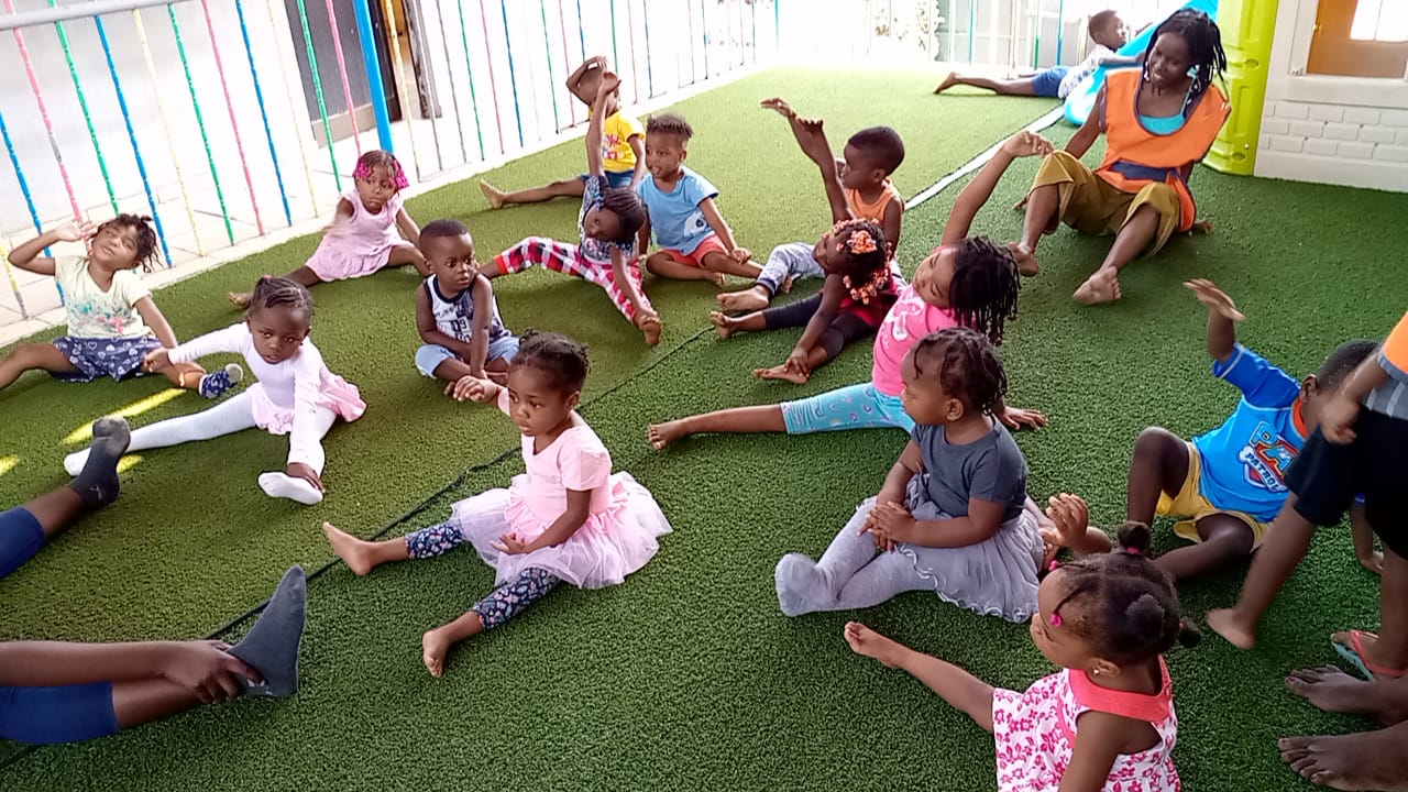 Crianças do Centro Infantil a fazer exercícios no pátio com a educadora